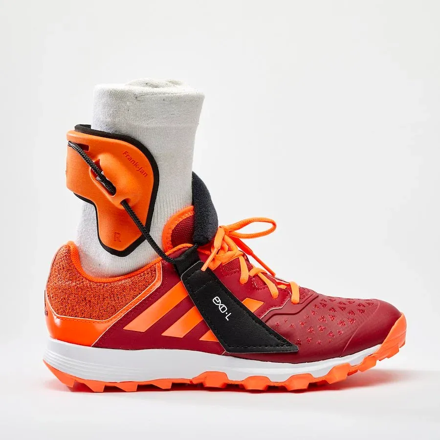 The EXO-L ankle brace worn on the outside of the ankle, its strap anchored to the shoe